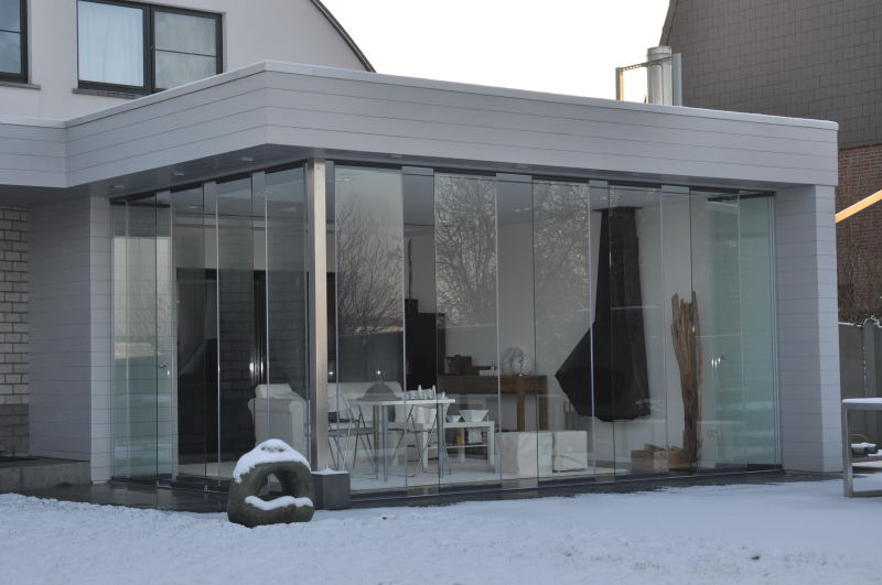 Extension contemporaine fermée par une baie accordéon Nova en aluminium fin, façade épurée sous lumière hivernale